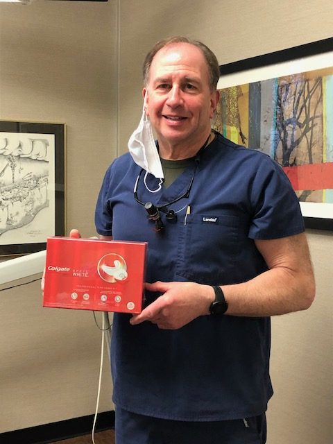 Dr. Gordon holding a box of the Colgate Optic White Professional Take-Home Whitening product
